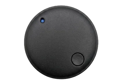A round black electronic tracker device with a textured matte finish, featuring a small blue LED indicator light and a central button, shown from a top-down view on a white background.